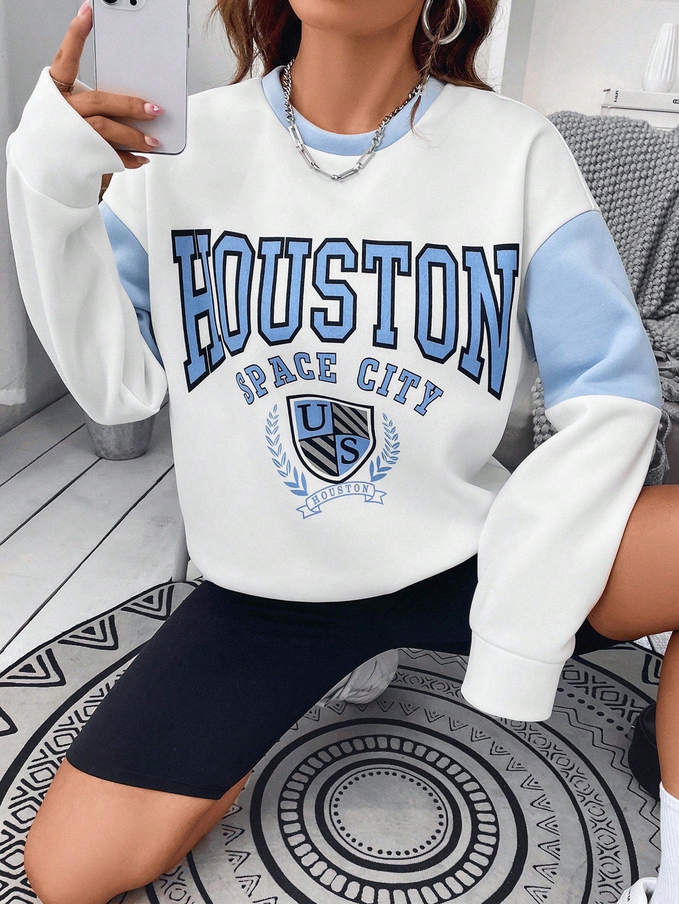 بلوفر رياضي ذو أكتاف متساقطة عليه رسمة حرفية