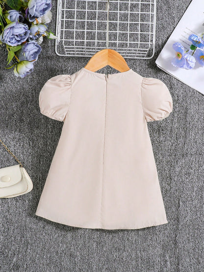 فستان قصير ذو أكمام قصيرة ورقبة دائرية وتصميم مربعات مرح وعصري. تناسب الفتيات الصغيرات، مزود بعقدة أنيقة ومناسبة لفصل الصيف