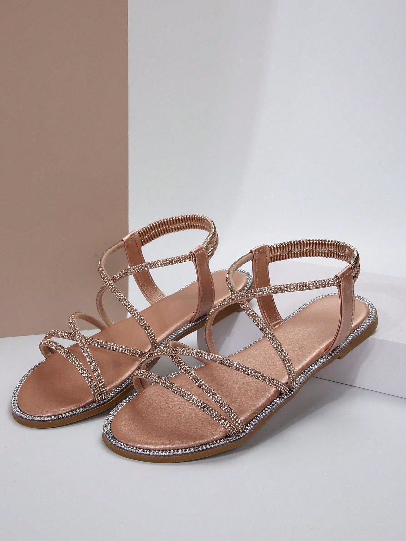 صنادل مسطحة برأس مدور وتفاصيل معدنية ومرصعة بالراين، حزام كاحل مطاطي، استيل روماني للنساء